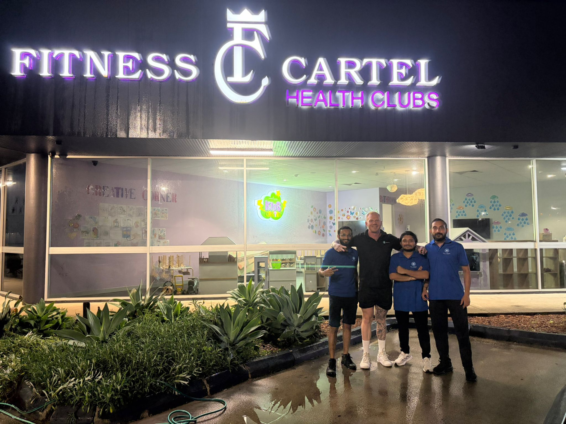 A New Era site team standing together with the venue manager outside a health club they service at night
