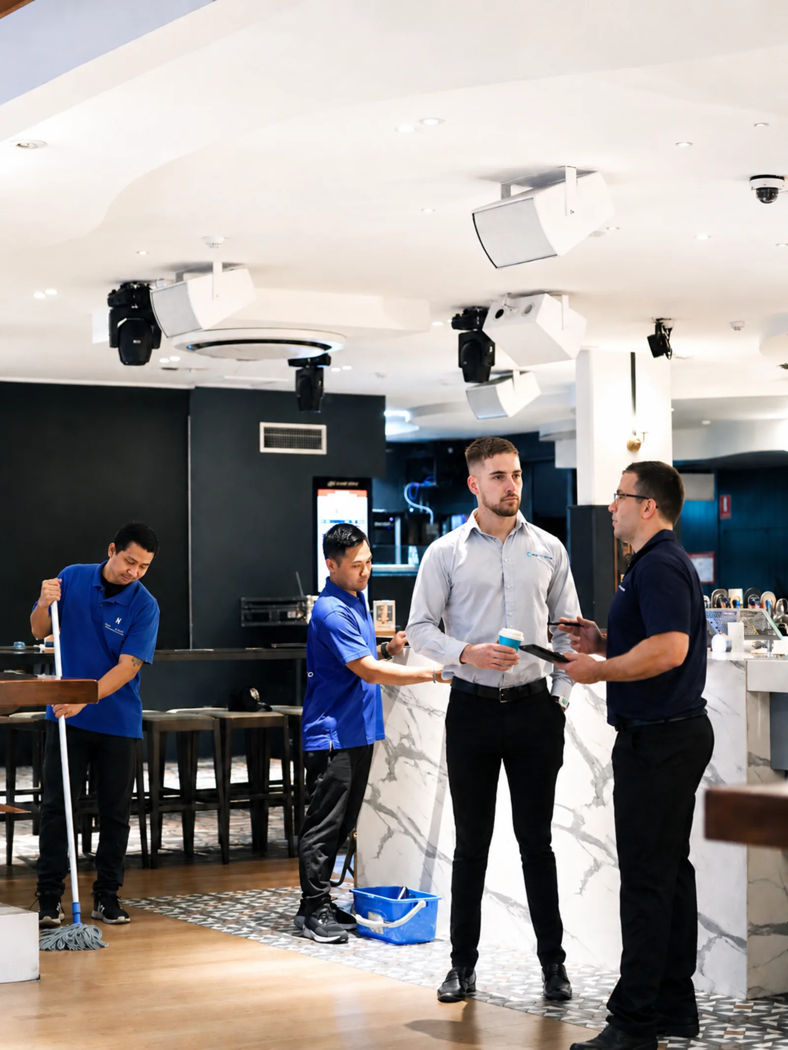 New Era supervisors briefing a cleaning team inside a hospitality venue before service