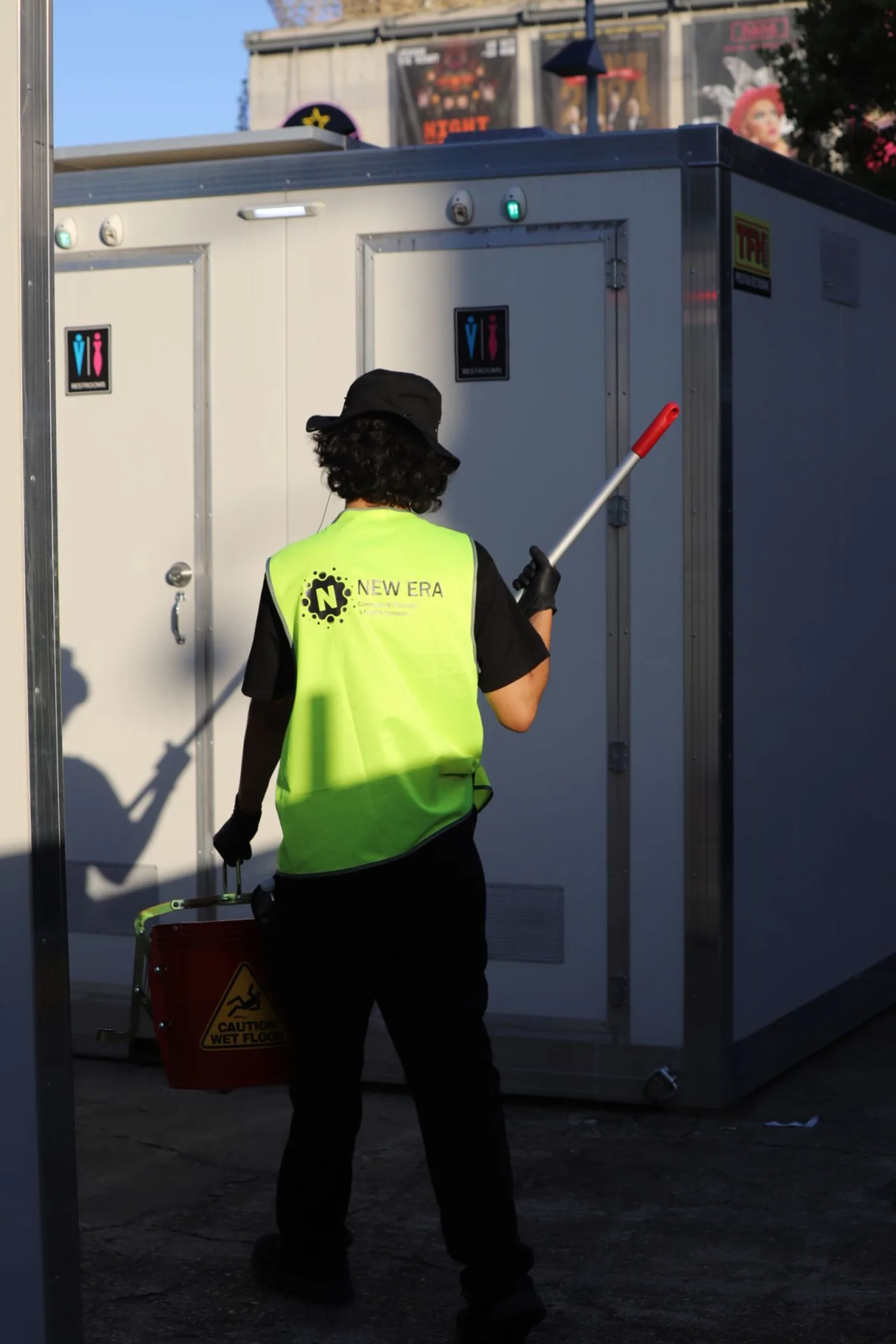 New Era attendant carrying cleaning equipment to service event amenity blocks