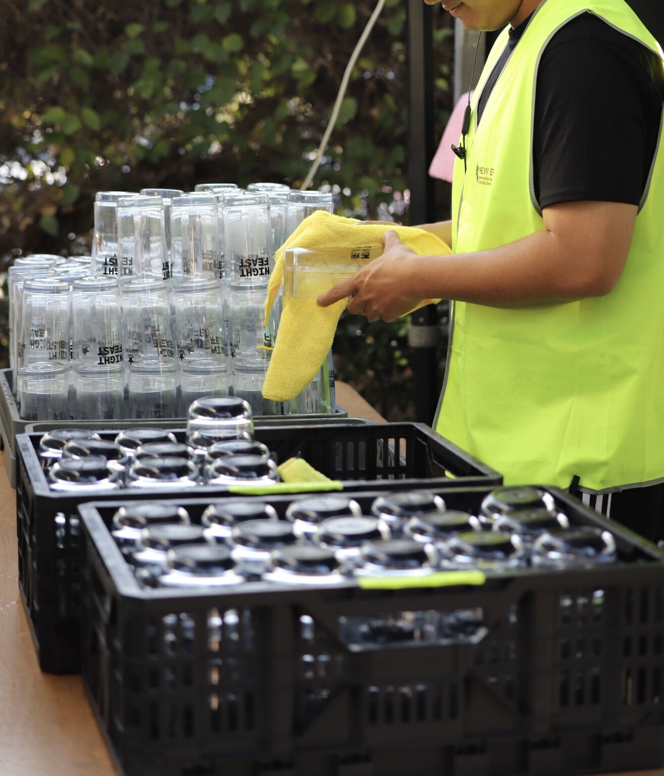 New Era team member hand-drying branded Night Feast reusable glasses in crates for redistribution to vendors