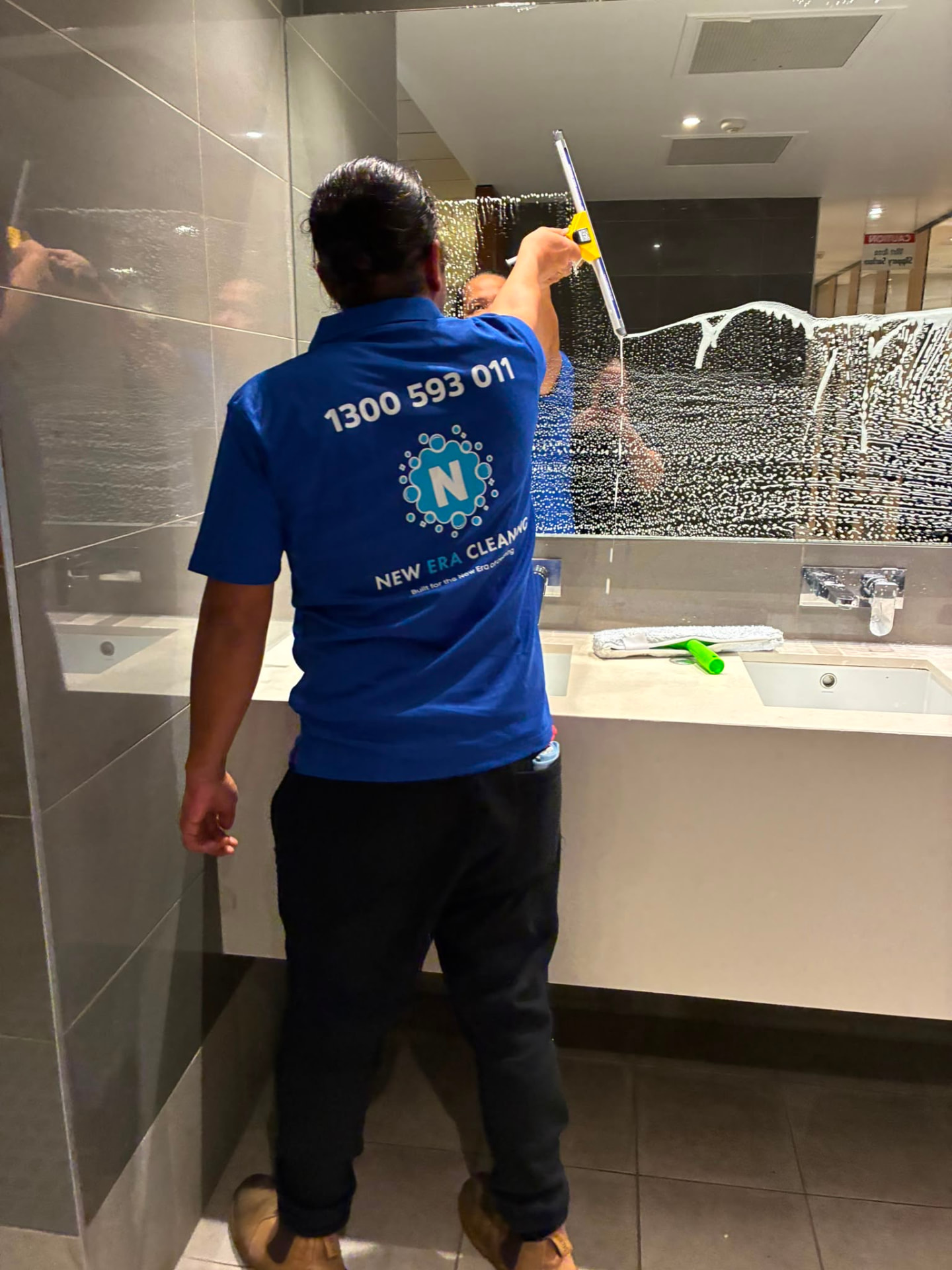 New Era team member cleaning mirrors during an Adelaide hospitality mobilisation
