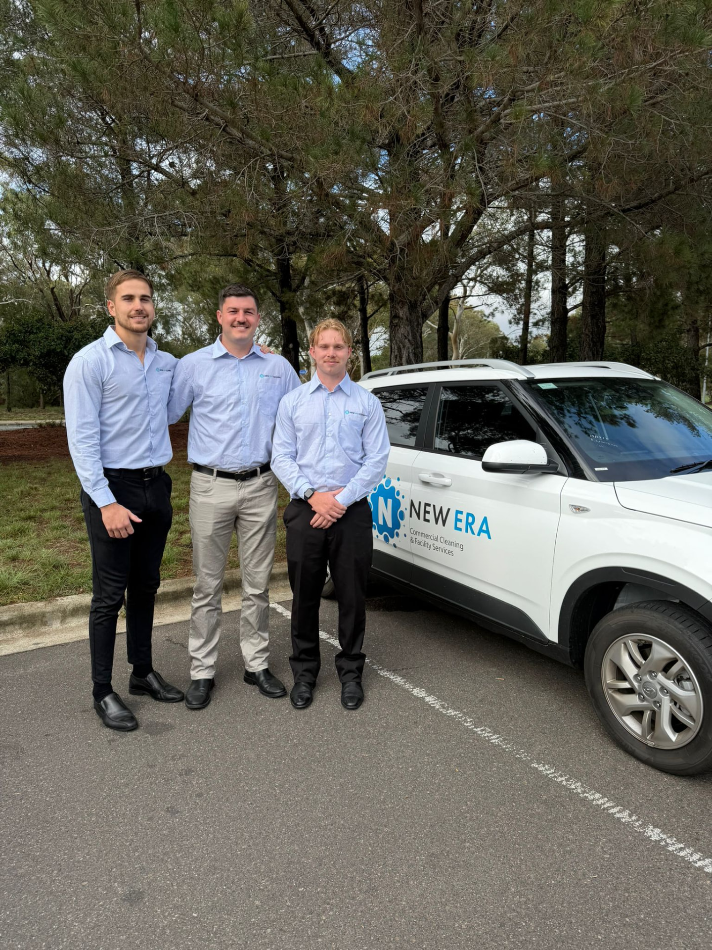 Three New Era managers in branded business shirts standing beside a branded New Era service vehicle